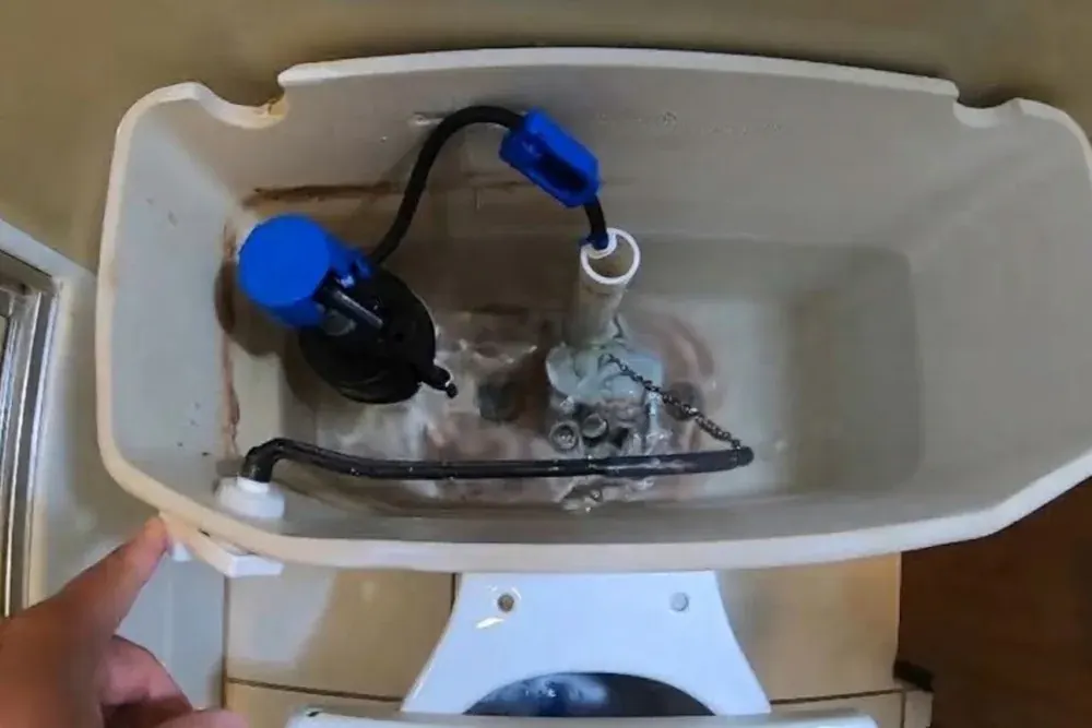 Open toilet tank showing a blue fill valve, float and flapper